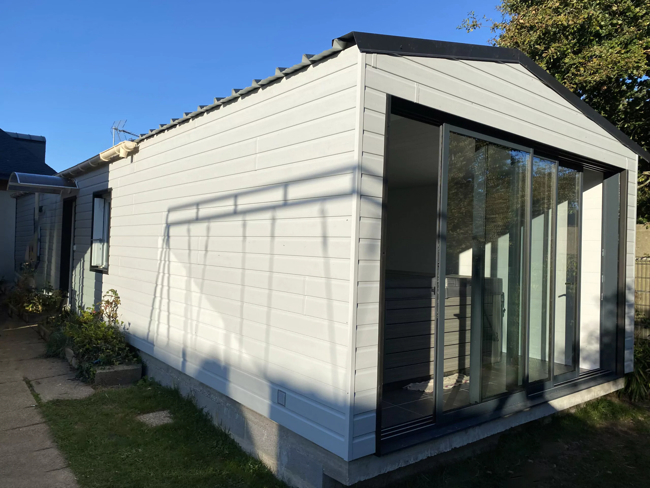 Extension ossature bois, toiture double pente en bac acier anti-condensation. Bardage extérieur en PVC double lame. Lambris blanc pour les finitions intérieures